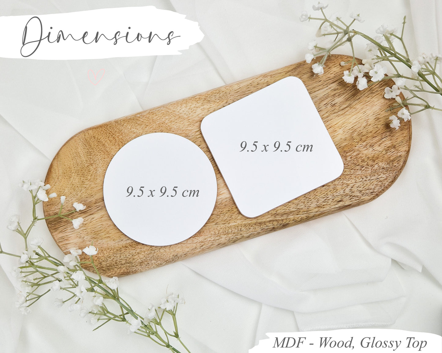 Two wooden MDF coasters with dimensions on a wooden board with flowers.