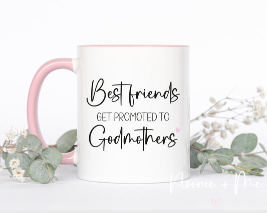 Mug with 'Best friends get promoted to Godmothers' text on a white background with pink handle and floral decorations.